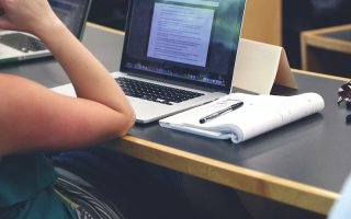 person siting at a desk with laptop and notebook
